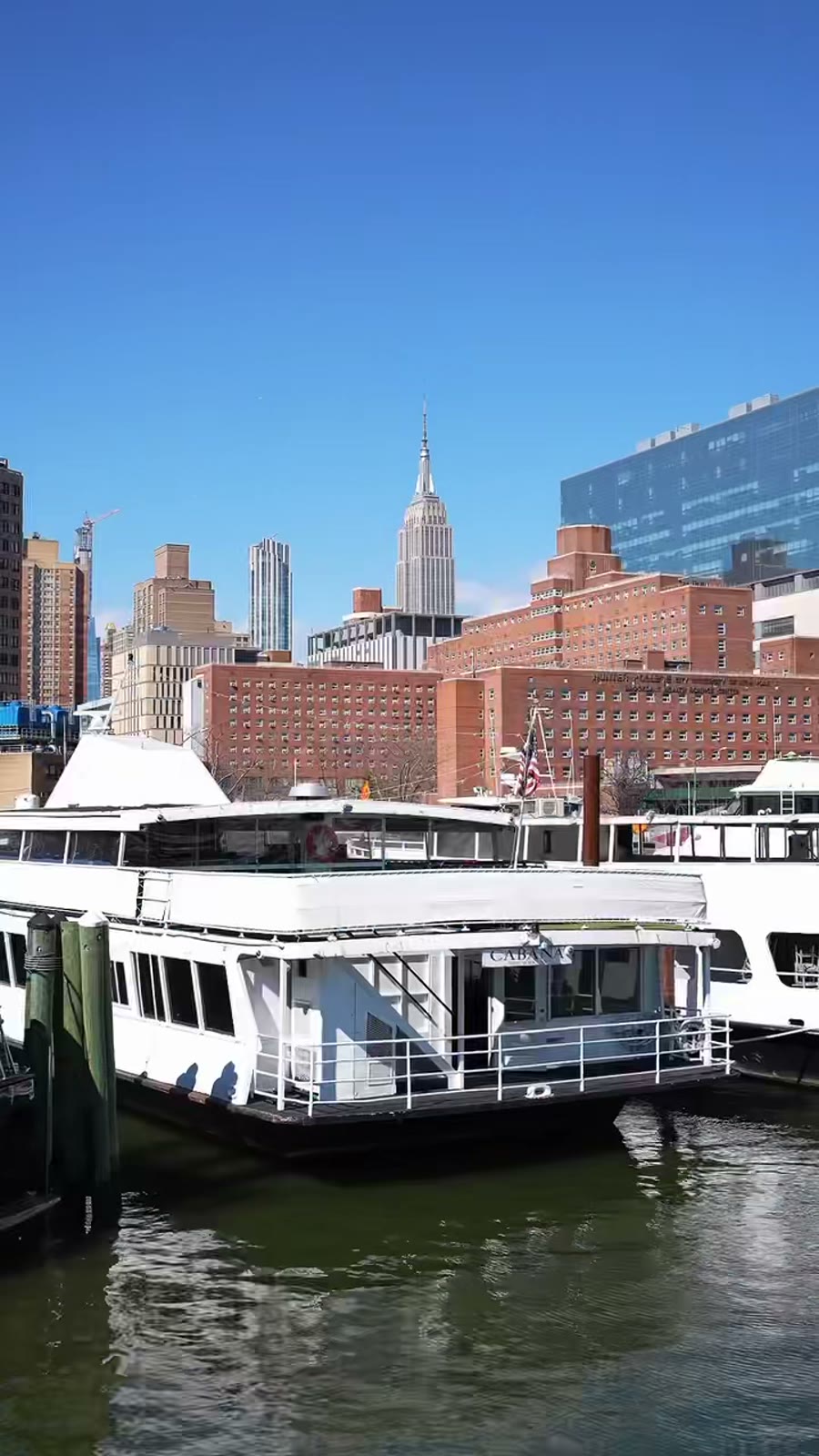 Cabana, Harbor Social's largest charter vessel, docked in New York with the Empire State Building behind it