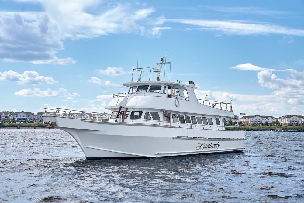 Kimberly, a Harbor Social charter yacht, underway near New York with a bridge and the skyline behind it
